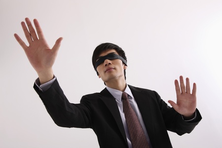 Man wearing blindfold reaching out handsの写真素材