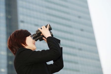 Businesswoman looking through binocularsの写真素材