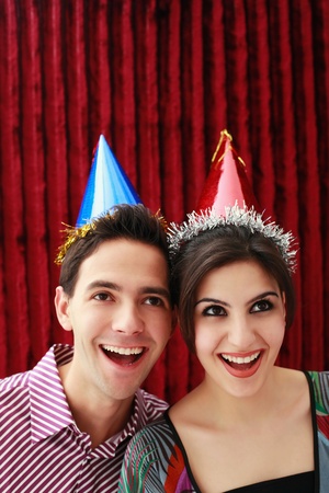 Man and woman with party hats smiling while looking upの写真素材