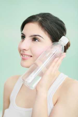 Woman placing a bottle of water next to her faceの写真素材