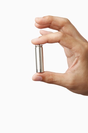 Human hand holding a battery in between fingers