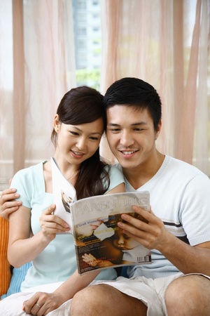 Man and woman reading magazineの写真素材