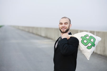 Businessman carrying a bag of money on his backの写真素材