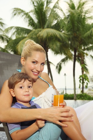 Woman and boy sitting on lounge chair smilingの写真素材