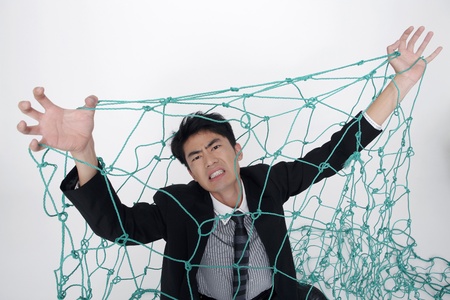 Businessman trapped under a netの写真素材