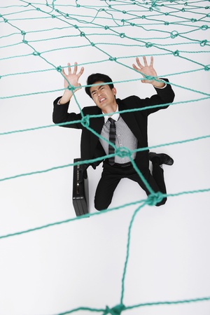 Businessman trapped under a netの写真素材