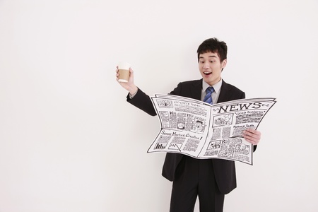 Businessman reading newspaper and holding a cup of coffeeの写真素材