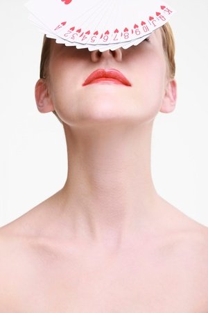 Woman with fanned out playing cards on her faceの写真素材