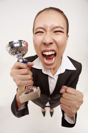 Businesswoman holding trophy, celebratingの写真素材