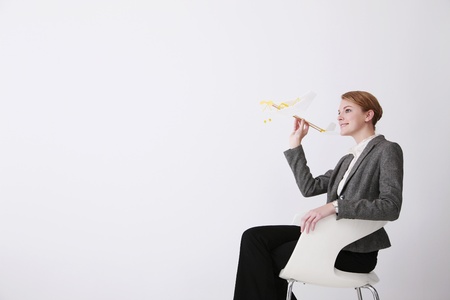 Businesswoman playing with model airplaneの写真素材