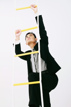 Businessman climbing up rope ladderの写真素材