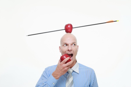 Man eating apple with apple pierced by arrow balanced on his headの写真素材
