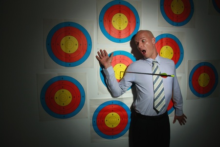 Businessman on target with arrow next to himの写真素材