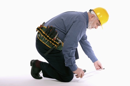 Man with hardhat measuring floor with tape measure