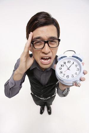 Businessman crying while holding alarm clockの写真素材