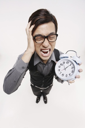 Businessman screaming while holding alarm clockの写真素材