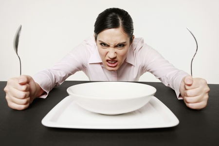 Businesswoman sitting at table looking angryの写真素材