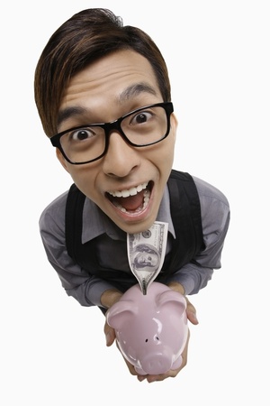 Businessman looking excited while holding piggy bank with moneyの写真素材