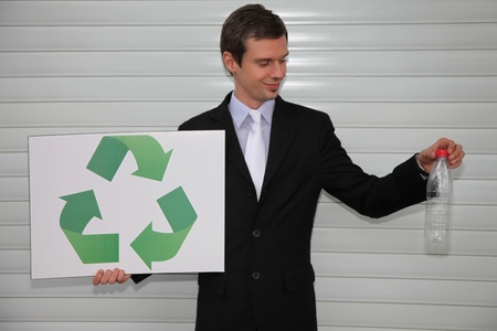 Businessman holding a card with recycling symbol and a plastic bottleの写真素材