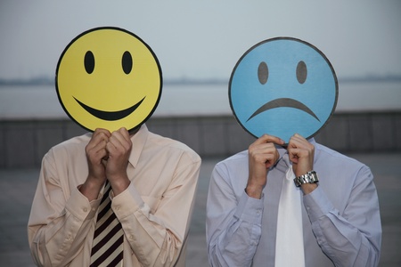 Businessmen holding expression masks over their facesの写真素材