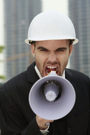 Businessman with hard hat screaming into megaphoneの写真素材