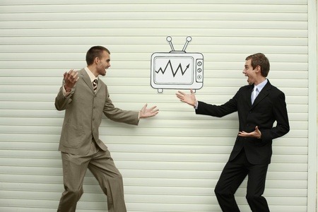 Businessmen looking at television for stock market updatesの写真素材