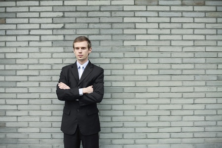 Businessman standing in front of brick wallの写真素材