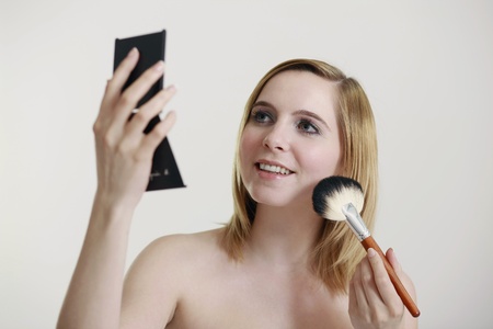 Woman applying blusher on her cheeksの写真素材