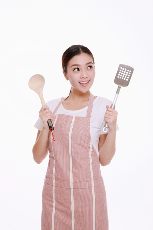 Woman in apron holding cooking utensilsの写真素材