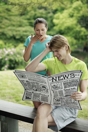Man and woman reading newspaperの写真素材
