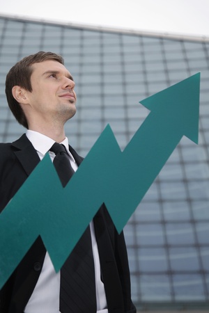 Businessman smiling, arrow pointing up in front of himの写真素材