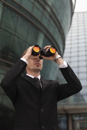 Businessman looking through binocularsの写真素材