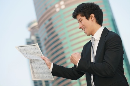 Businessman cheering while reading newspaperの写真素材
