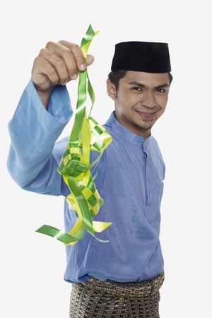 Man in traditional clothing holding ketupatの写真素材