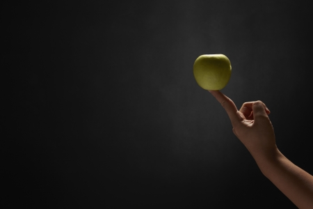 Green apple placed on a human fingerの写真素材