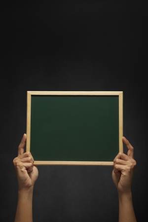 Human hand holding up a blank blackboardの写真素材