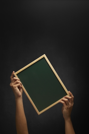 Human hand holding up a blank blackboardの写真素材