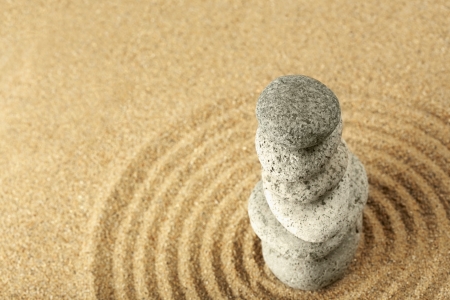Stack of pebbles on the wave pattern in the sandの写真素材