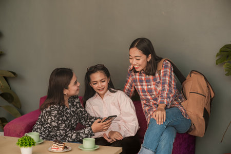 Women chatting in a cafe while looking at smartphone