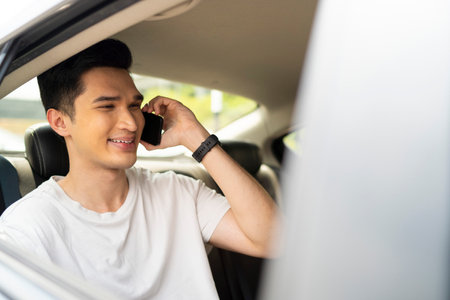 Young Asian man inside a car talking on phone while traveling