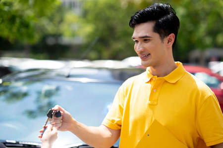 Young Asian man car dealer smiling and holding car keysの写真素材