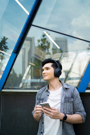 Young Asian man enjoying music outdoors