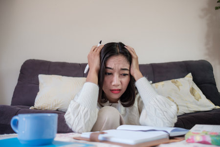 Young Asian woman feeling stressed and worried while study at home