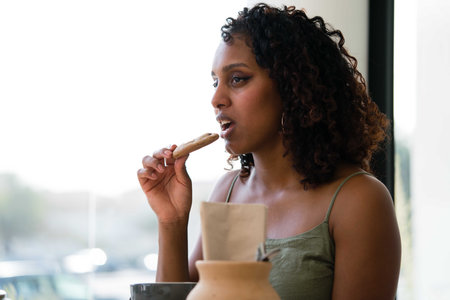 Young woman eating cookie while chatting with friends