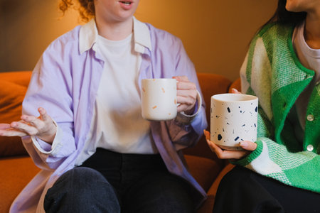 Young women with mugs chatting indoors