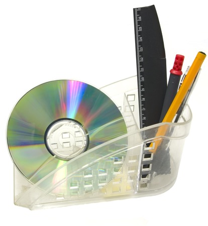 Close up of a CDROM, pen, ruler in plastic cup.