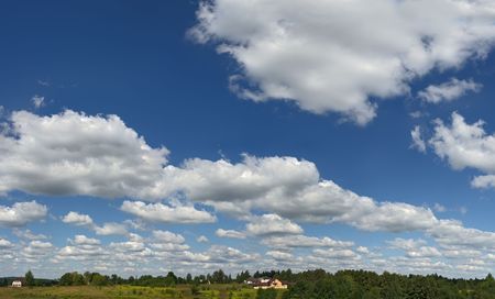 High clouds on high sky. Small houses near horizont.の写真素材