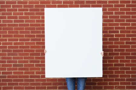blank board held ready for text in front of brick wallの写真素材