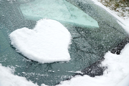 snow in heart shape on windshield of the carの写真素材