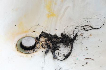 cleaning water sink clogged by hair in bathroomの写真素材